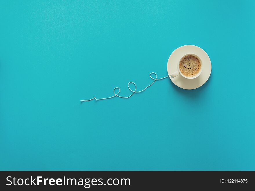 Coffee cup in shape of balloon with clouds on blue paper background