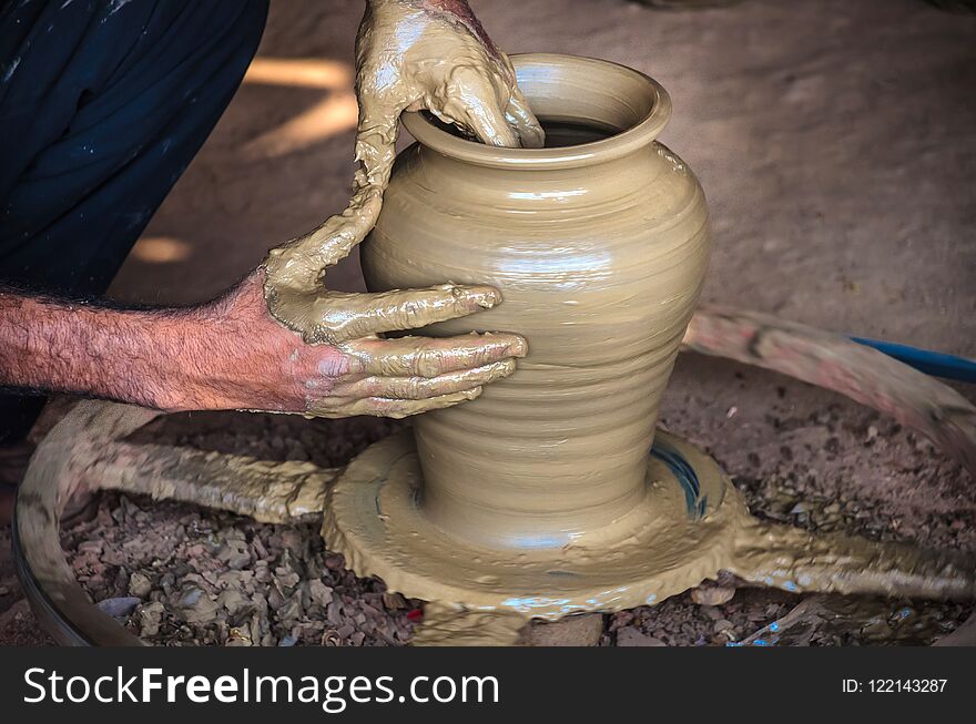 Closeup of potter`s hands making clay water pot on pottery wheel.