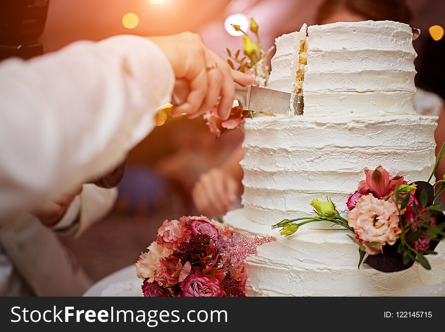 A bride and a groom is cutting their wedding cake. beautiful cake. nicel light. wedding concept. A bride and a groom is cutting their wedding cake. beautiful cake. nicel light. wedding concept