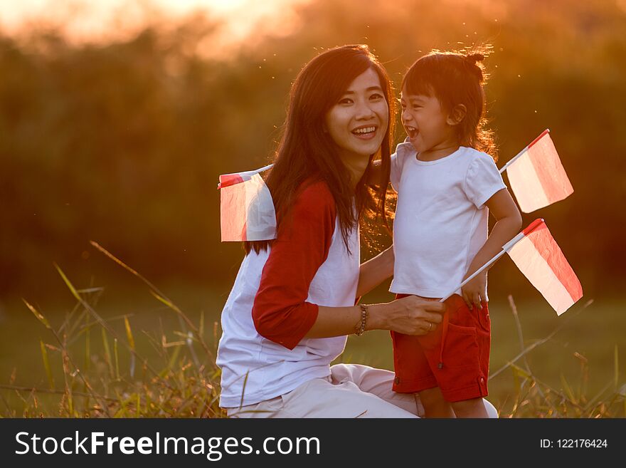 Mother and daughter raising flag of indonesia