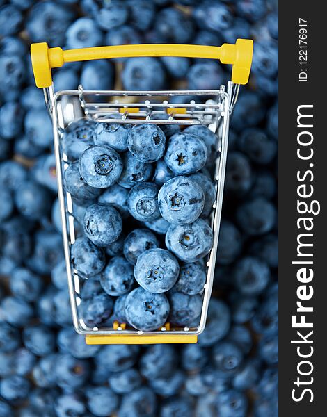 Blueberry fruits in mini shopping cart. Selective focus on the blueberries in small trolley