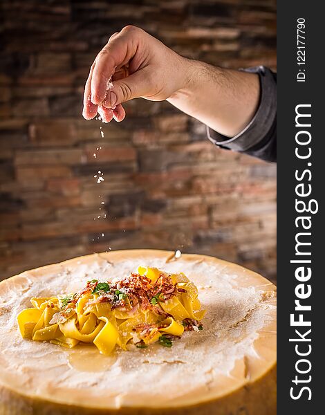 Chef in restaurant exclusively preparing italian pasta pappardelle on a block cheese parmesan. Chef in restaurant exclusively preparing italian pasta pappardelle on a block cheese parmesan.