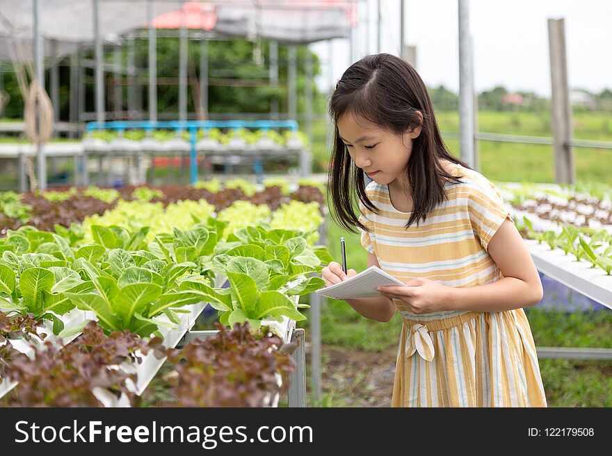 Asian cute girl is learning to grow organic vegetables in the fa