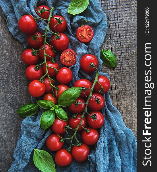 Fresh cherry tomatoes and basil leaves on a old wooden background