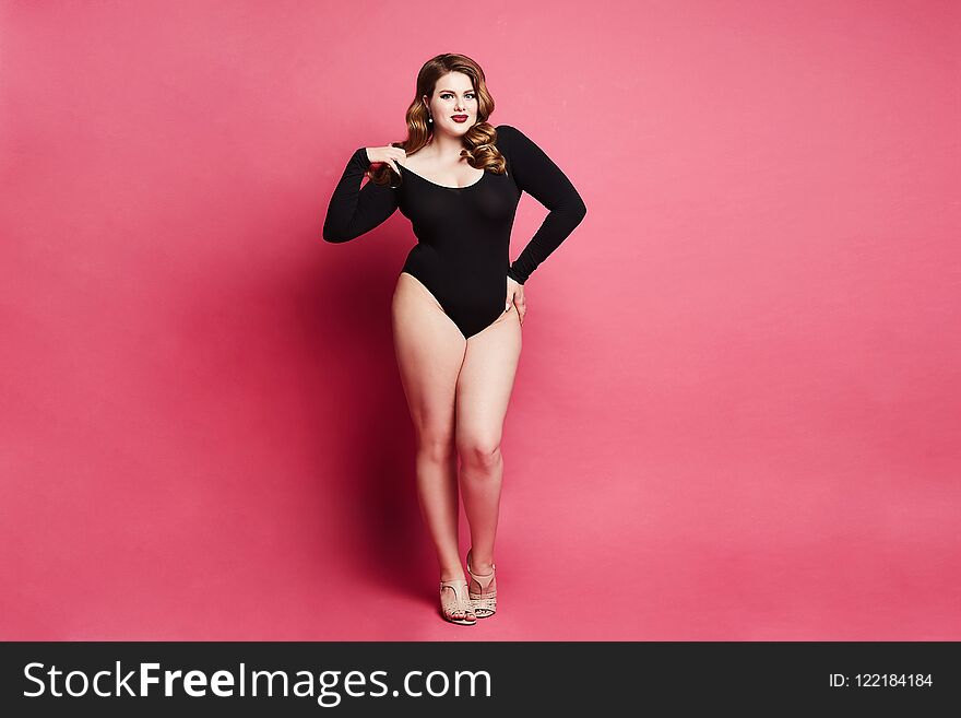 Plus size model girl, fashionable blonde in black bodysuit, with bright makeup and with stylish hairstyle, smiling and posing