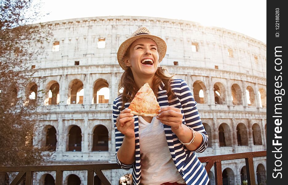 Smiling tourist woman with slice of pizza looking into distance