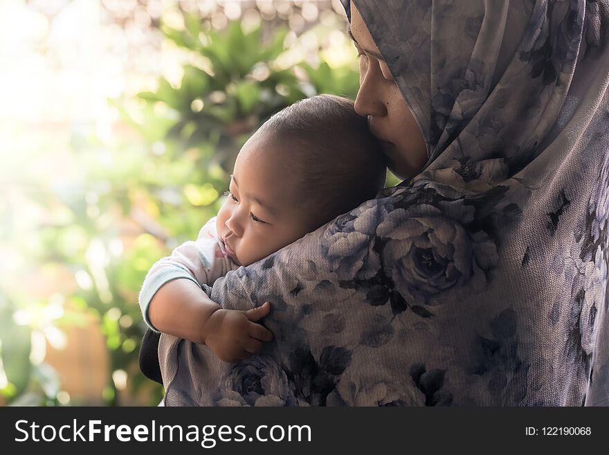 A Muslim mother from Indonesia wearing hijab holding her baby daughter. A Muslim mother from Indonesia wearing hijab holding her baby daughter