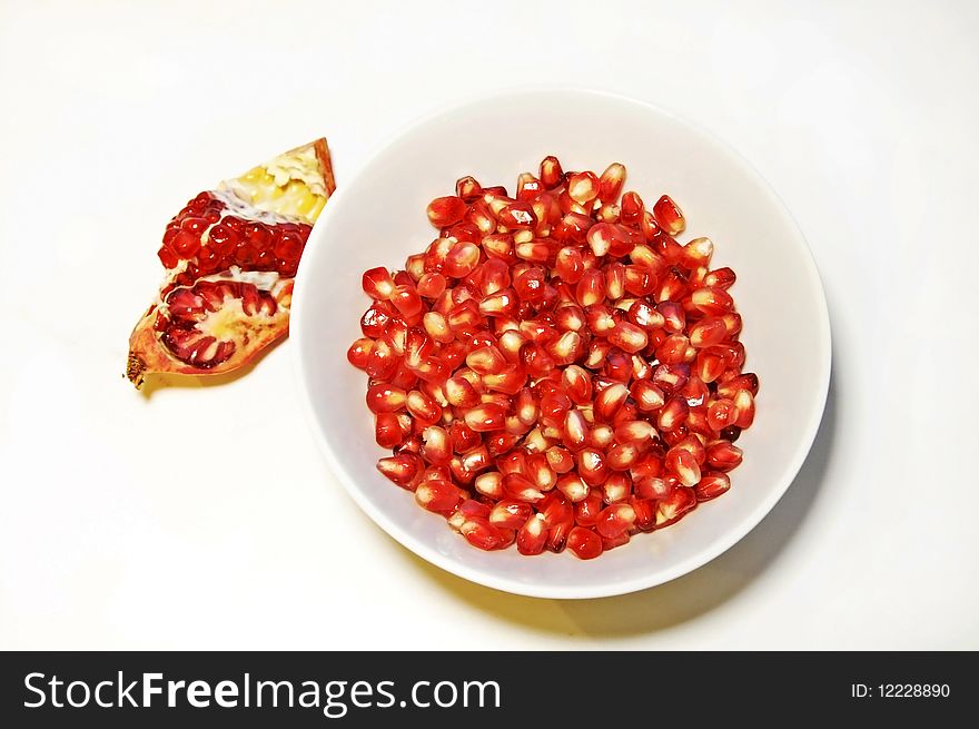 Pomegranate seeds in a bowl on a white background, high dynamic range