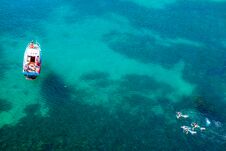 Aerial Shot Of Turquoise Water Lagoon At Hot Summer Day With White Boat And People Swimming Around The Boat. Stock Images Aerial Shot Of Turquoise Water Lagoon At Hot Summer Day With White Boat And People Swimming Around The Boat. Stock Images
