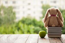 Toy Bunny Sitting Back, Lie Next To A Stack Of Books And A Green Apple. Concept In Anticipation Of The New School Year. Stock Photos