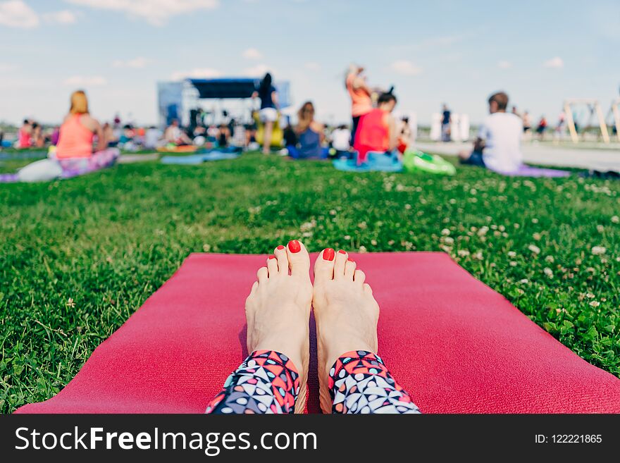 Female feet with red nails on a pink yoga Mat on the grass , a l