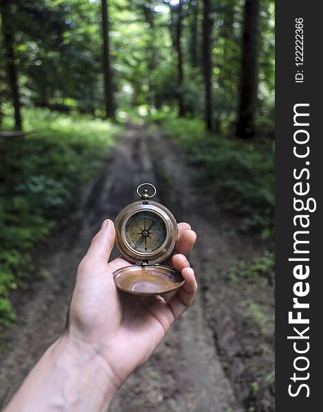 Man with compass in hand in lush summer forest. Travel concept