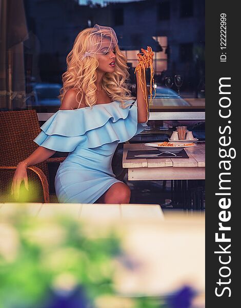 Food, people and leisure creative concept - beauty blonde young woman eating pasta in cafe. Food, people and leisure creative concept - beauty blonde young woman eating pasta in cafe