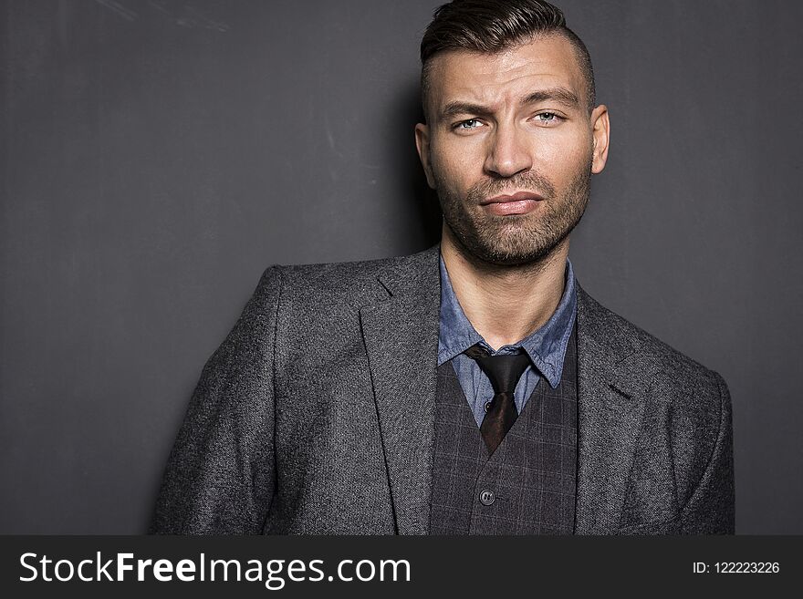 Portrait of stylish, elegant young man in suit with an impudent and prejudiced expression. Brutal young businessman.