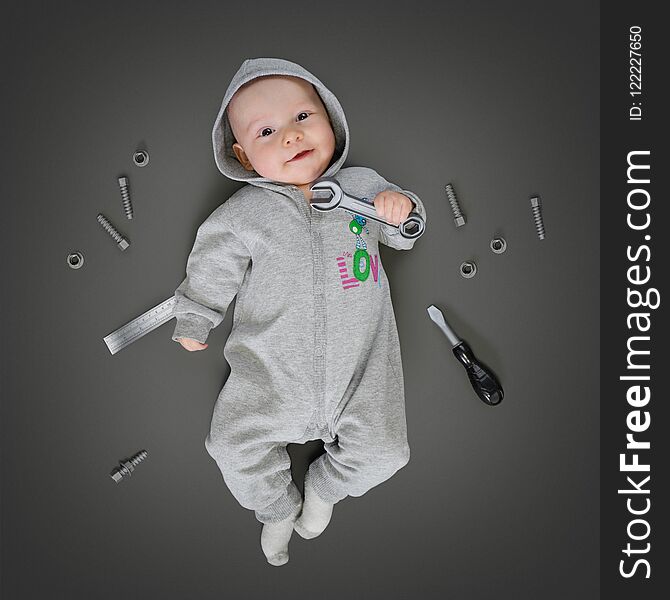 Baby in grey costume lying on a play mat and pretending he is a real repairer