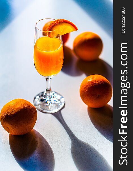 Fresh vivid colorful oranges on a white table and a glass of freshly squised orange juice. Copy space.