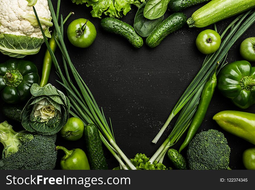 Heart shaped vegetables. Food photography of heart made from different vegetables on black background. Copy space, top view