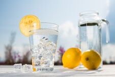 Glass Of Ice And Water Decorated With A Slice Of Lemon Standing On A White Table Against A Decanter With Water And Two Stock Image Glass Of Ice And Water Decorated With A Slice Of Lemon Standing On A White Table Against A Decanter With Water And Two Stock Image
