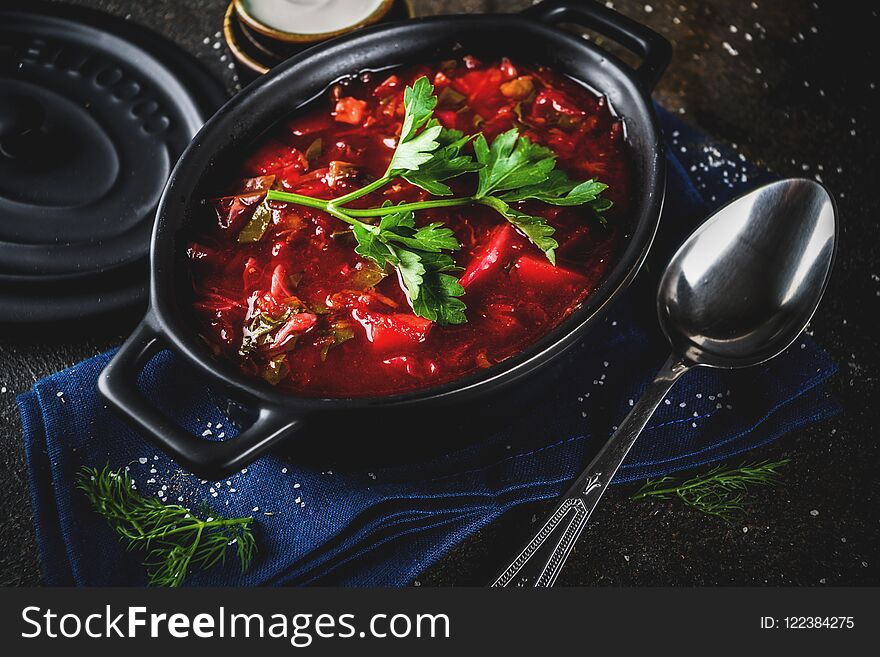 Ukrainian Russian traditional hot dish - borsch soup, with greens, garlic, rye bread, on a dark table. Ukrainian Russian traditional hot dish - borsch soup, with greens, garlic, rye bread, on a dark table