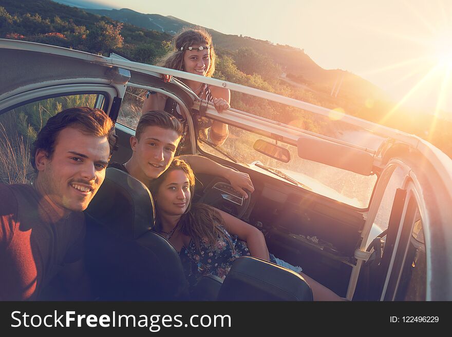 Group of happy people in a car at sunset in summer. Group of happy people in a car at sunset in summer.