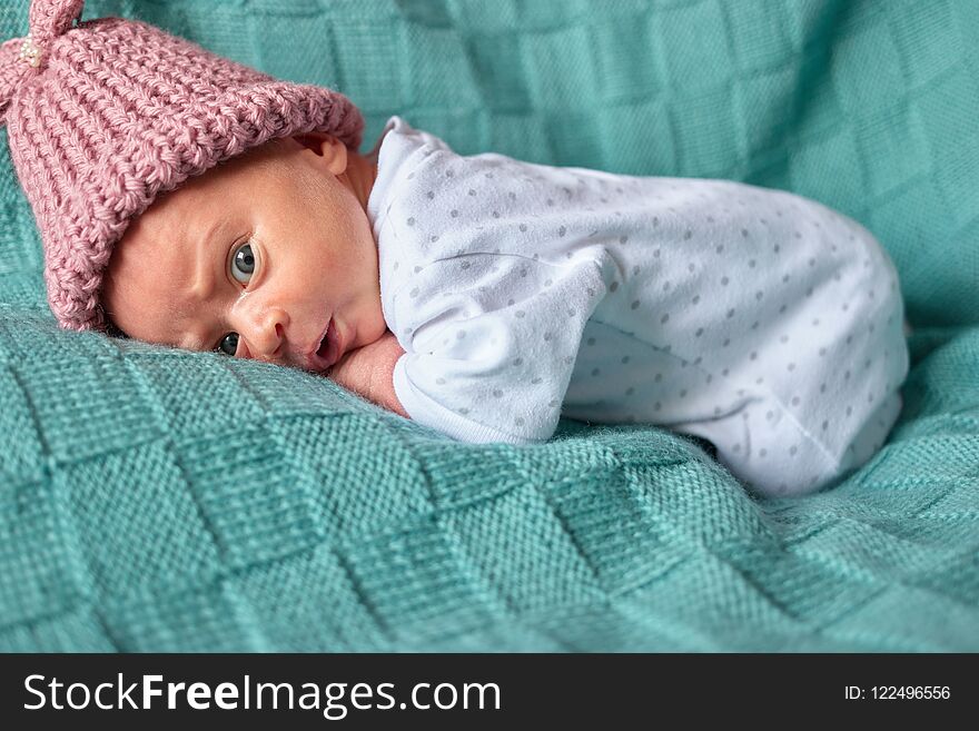 Newborn surprised baby girl in bed.