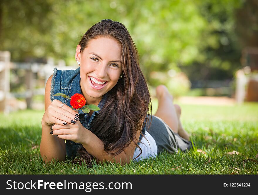 Laughing Mixed Race Teen Laying In Grass With A Flower