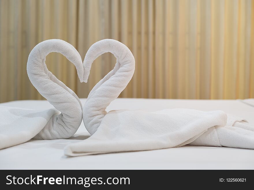 Close-up folded swans bird of fresh white bath towels on the bed sheet in the hotel.