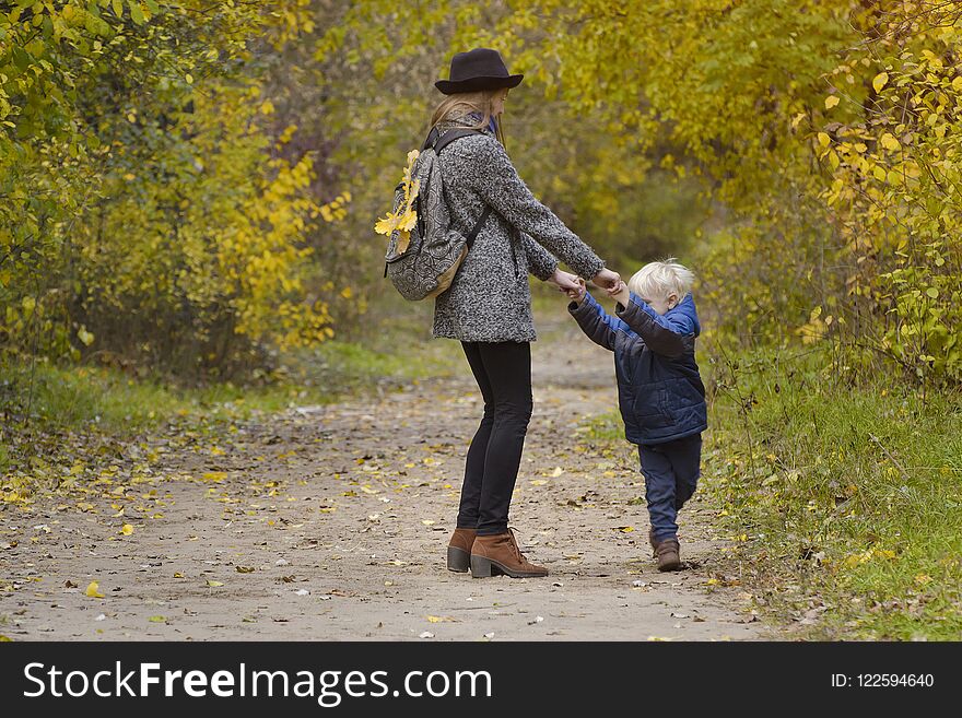 Mom And Son Are Playing In The Autumn Forest.