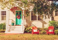 A Small Cozy Wooden Traditional American House With Wooden Chairs By The Porch. Autumn Sunny Day. Vintage Style. Stock Photo