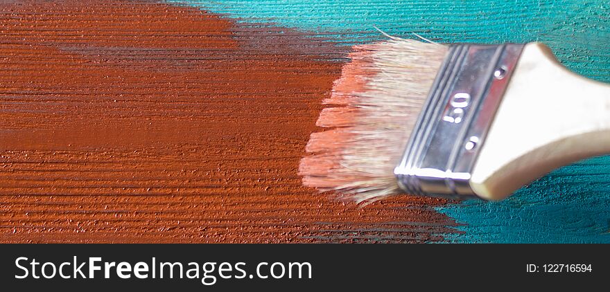 Banner. Brush with paint in hand. A man paints blue boards in a brown paint brush.