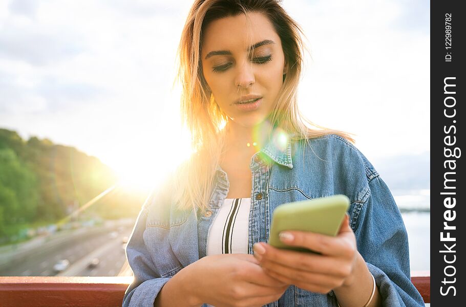 girl freelancer at sunset speaks on the phone and works.