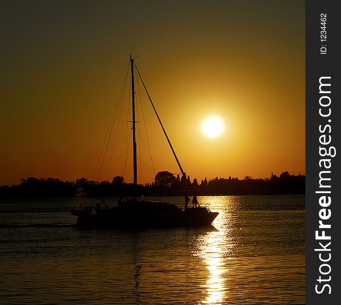 A wonderful sun down in the Venetian lagoon, with a sail boat gliding by. A wonderful sun down in the Venetian lagoon, with a sail boat gliding by.