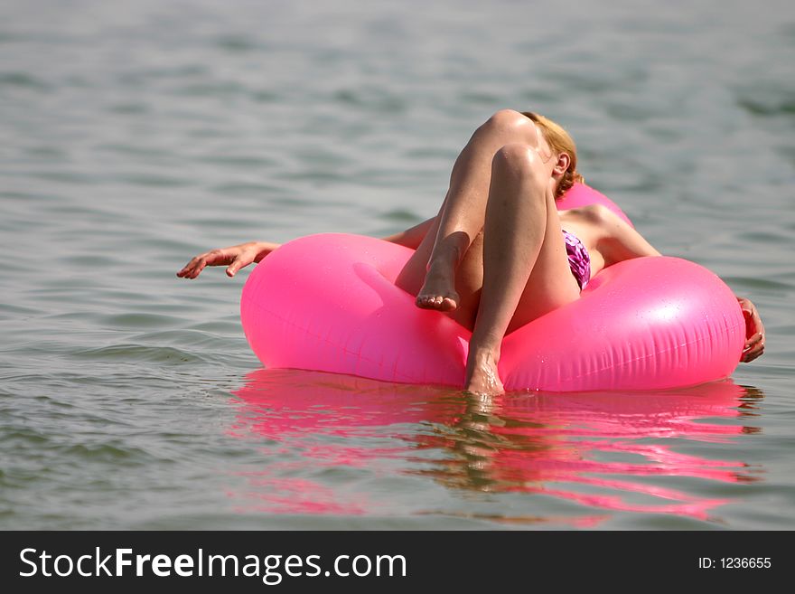 Women taking a sun bath on a pink raft. Women taking a sun bath on a pink raft