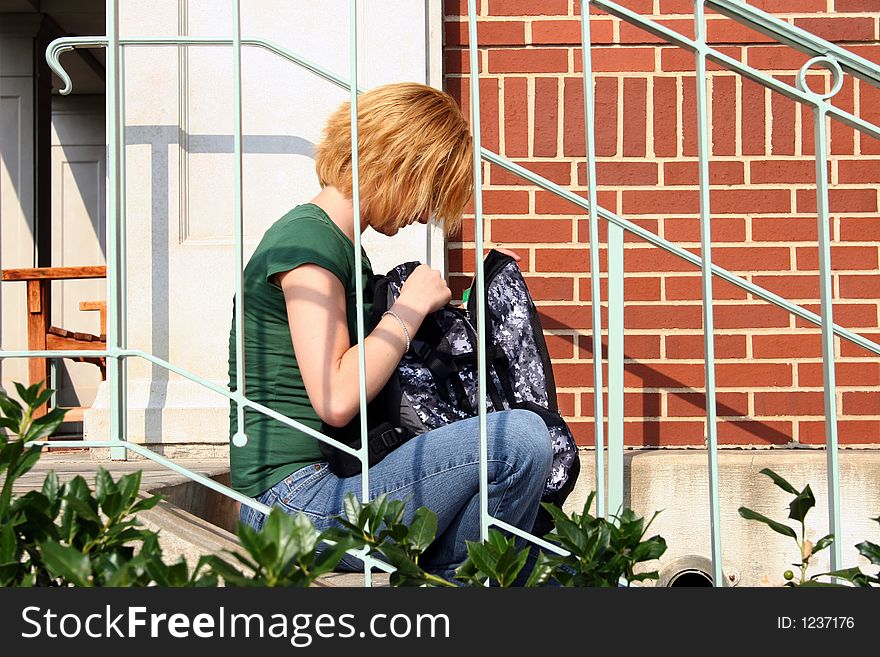 Young girl sitting on steps going through bag. Young girl sitting on steps going through bag