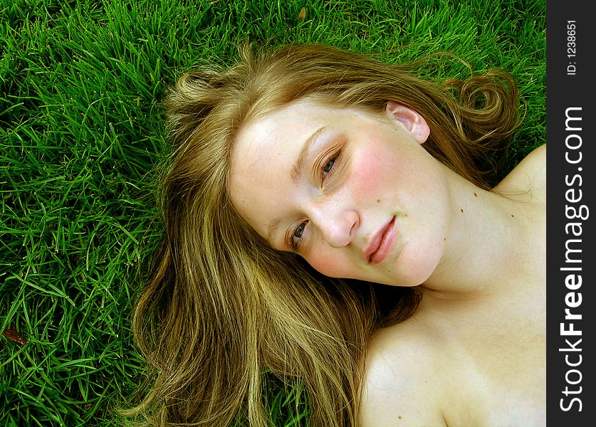 Young girl laughing sitting in grass. Young girl laughing sitting in grass