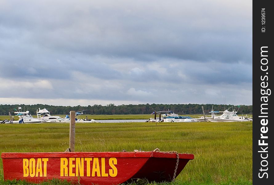 Rental Boats on small boat sitting by the road with large boats (in the water) in the background. Rental Boats on small boat sitting by the road with large boats (in the water) in the background