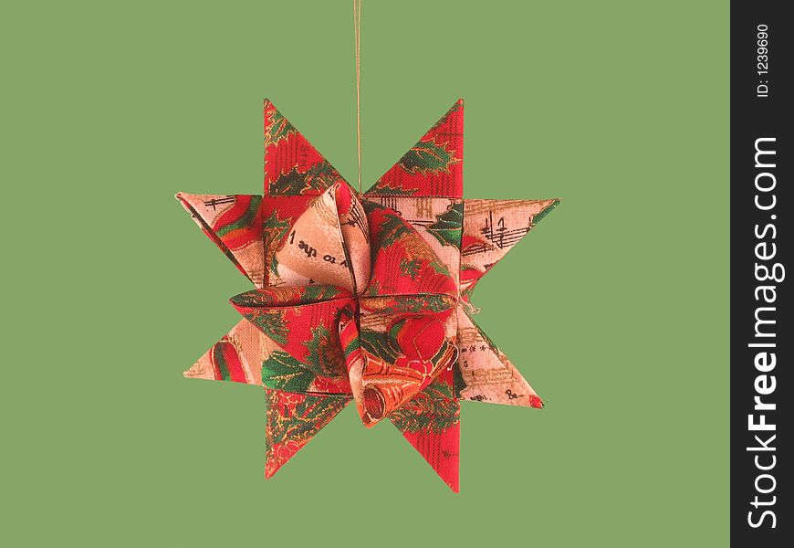 Red and Green Moravian Star Christmas Tree Ornament on a green background.