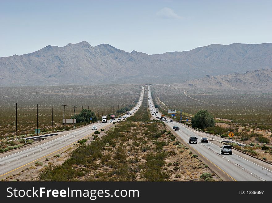 Four lane desert highway stretching to mountains