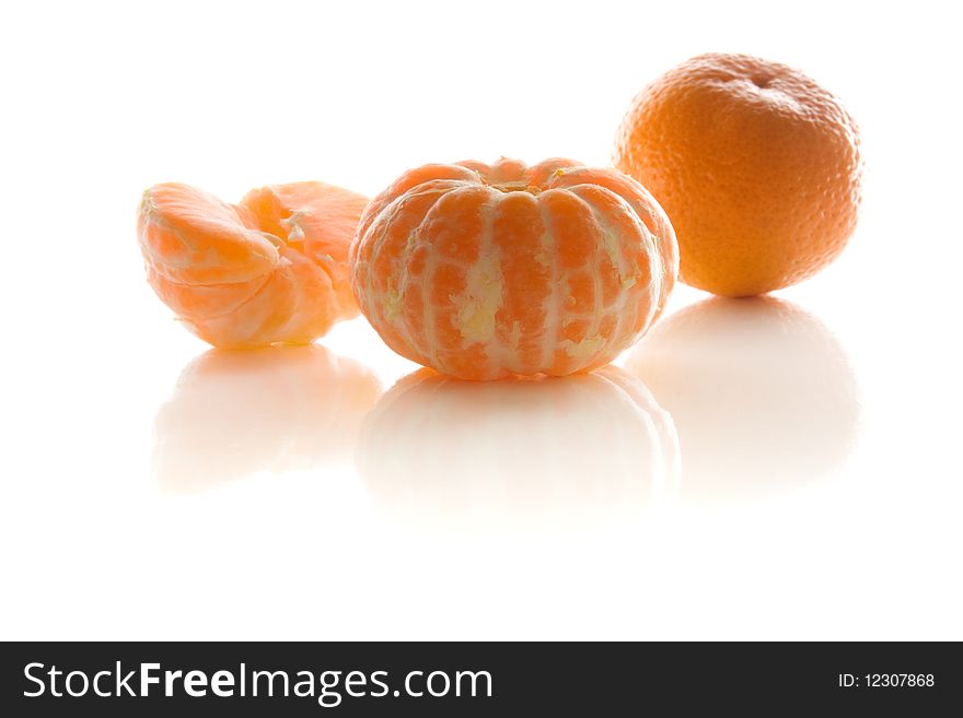 Peeled mandarins lie on the white reflecting surface