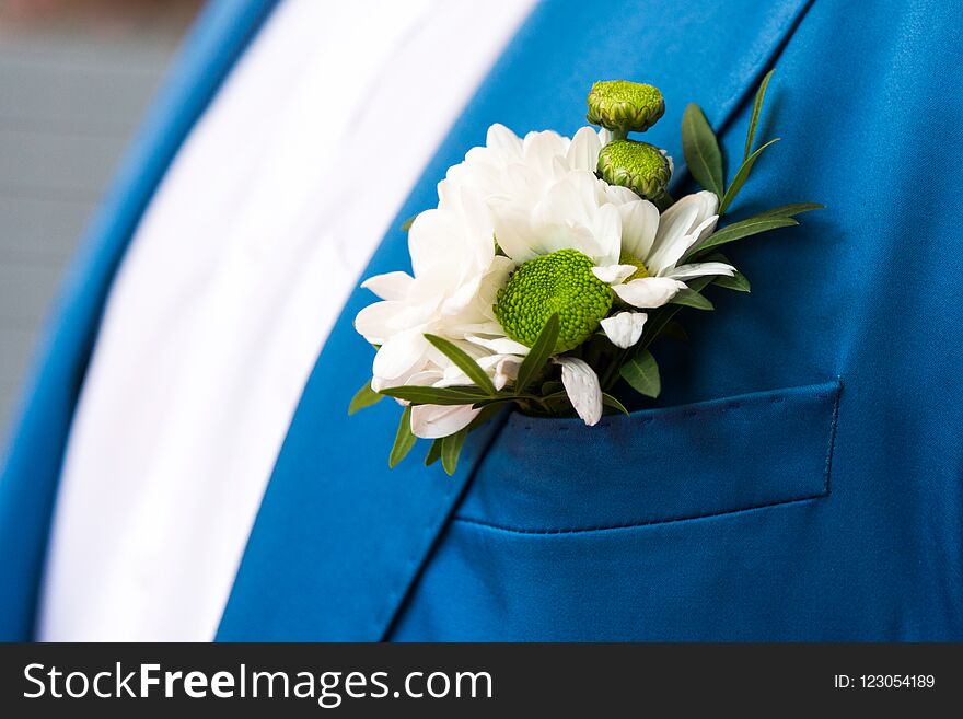 Groom in blue checkered suit with a white and pale pink rose boutonniere, close up