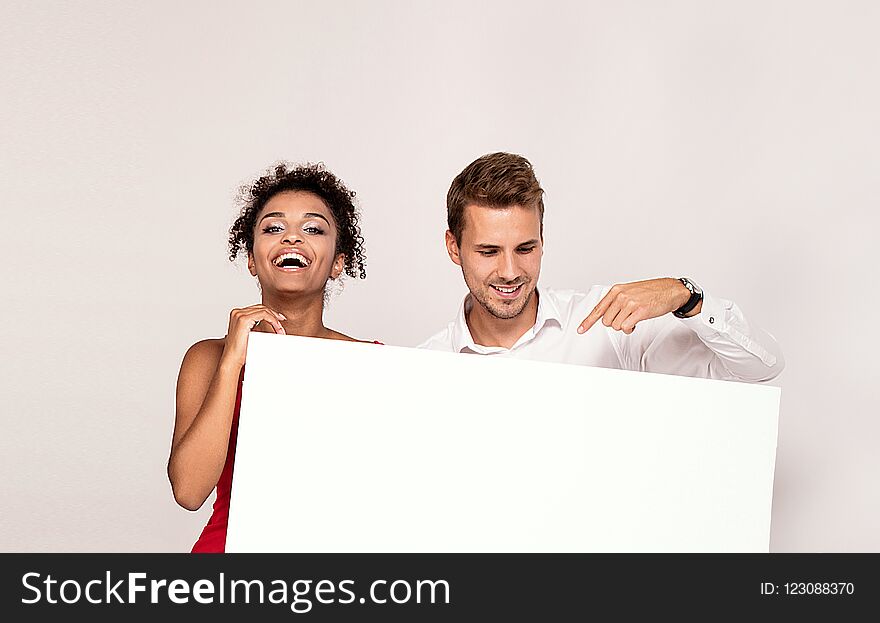 Happy young couple holding white banner with copy space. Man and women with blank board. Happy young couple holding white banner with copy space. Man and women with blank board.