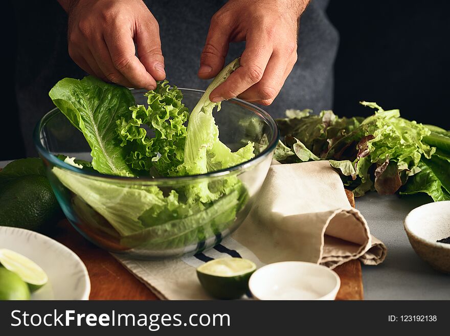 Man is cooking green detox salad of romaine lettuce. Healthy food concept. Man is cooking green detox salad of romaine lettuce. Healthy food concept