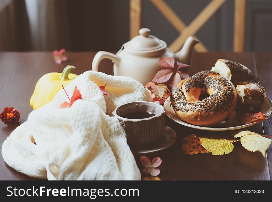 Cozy autumn breakfast on table in country house. Hot tea, pumpkins, bagels and flowers.