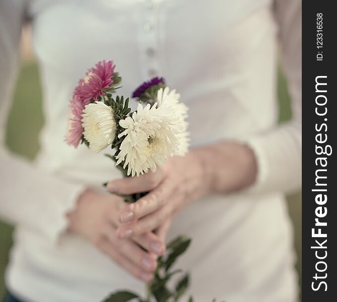 Women hands holding flowers in a rural field outdoors, lust for life