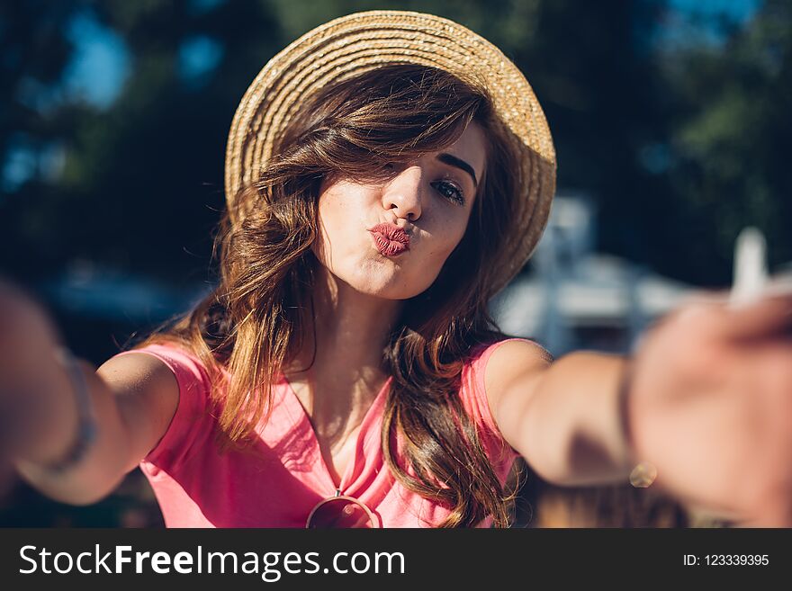 Close up portrait Nice laughing girl in hat, making selfie on the beach.Cute summer fashion portrait of beauty brunette woman havi