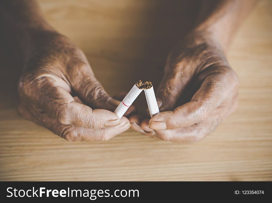 No smoking day concept with old male hand crushing cigarette