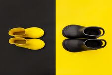 Two Pairs Of Gumboots - Yellow Female And Black Male - Standing Opposite To Each Other On The Inverse Backgrounds. Stock Images