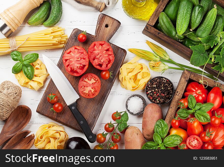 Fresh garden tomatoes and cucumbers with herbs cooking on wooden table. Top view