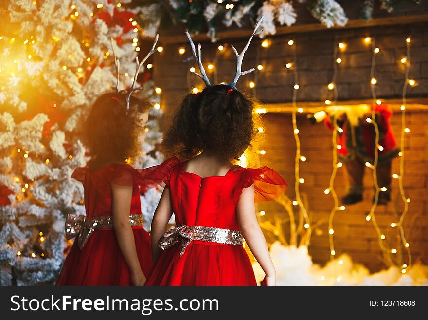 Two curly little girls looking at the christmas fireplace near b
