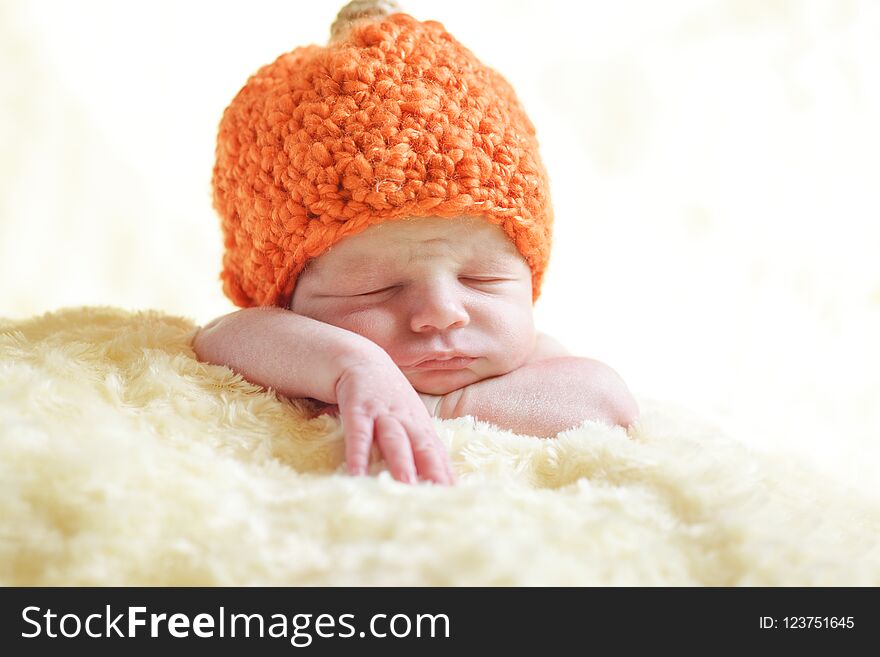 Newborn boy is wearing a pumpkin hat. Newborn boy is wearing a pumpkin hat